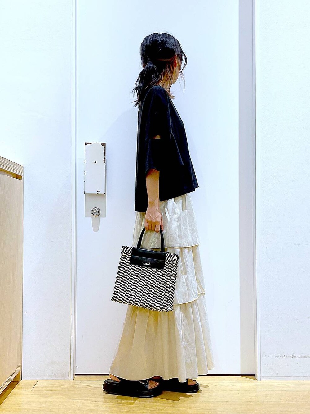 ブラック系のサンダル、ブラック系のショルダーバッグ、ゴールド系のスカートを着用したレディースの夏コーディネートの4枚目の写真