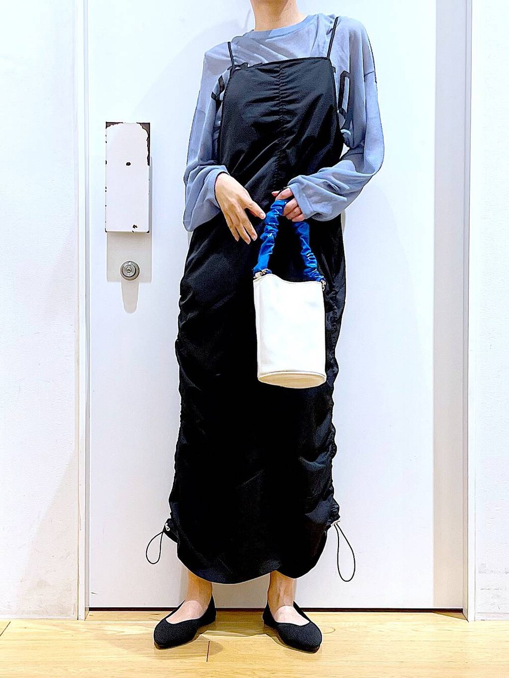 ブルー系のショルダーバッグ、ブラック系のパンプス、ブラック系のワンピースを着用したレディースの春コーディネートの6枚目の写真