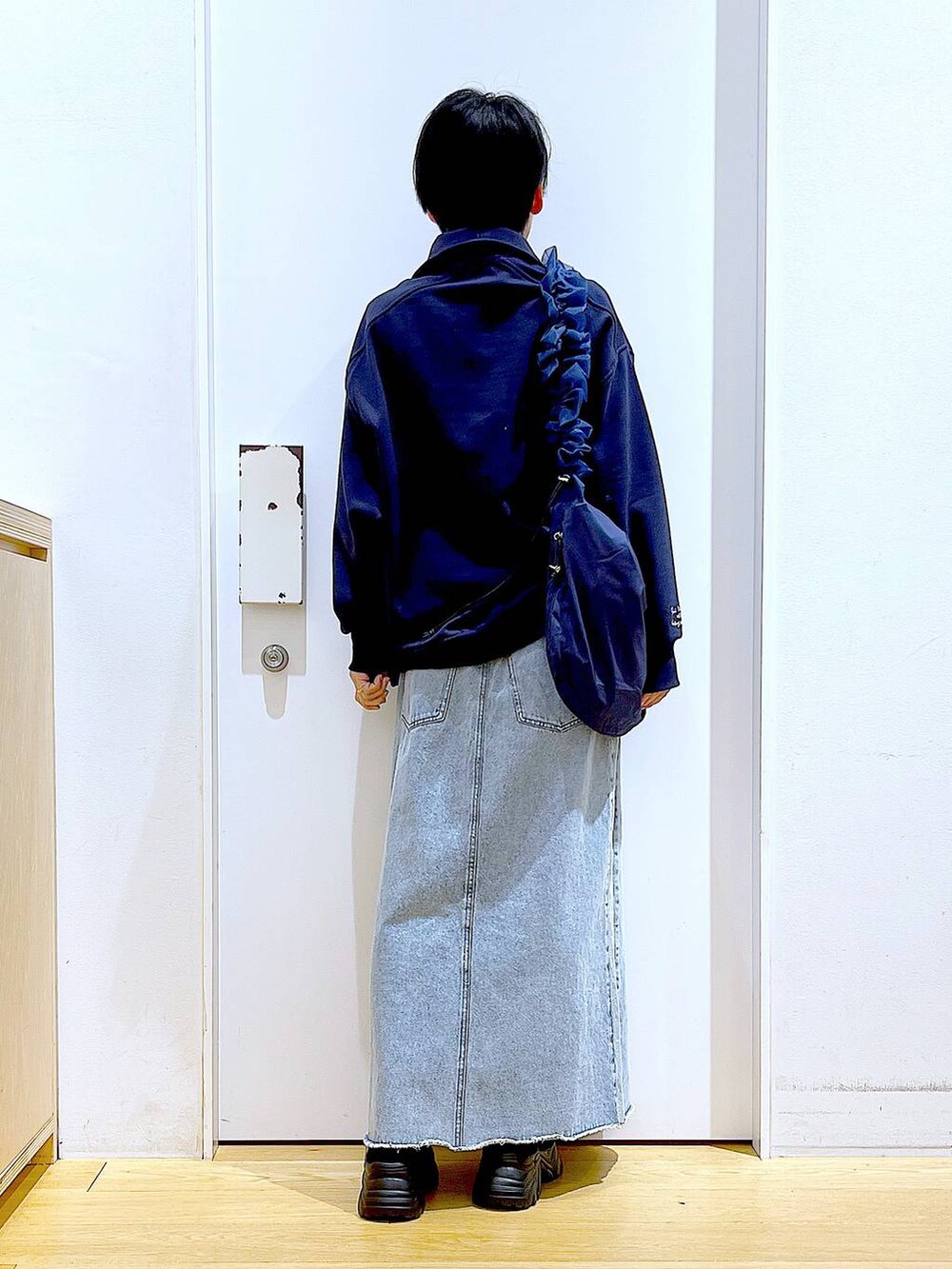 ブルー系のショルダーバッグ、ブラック系のブーツ、ブルー系のデニムスカートを着用したレディースの春コーディネートの5枚目の写真