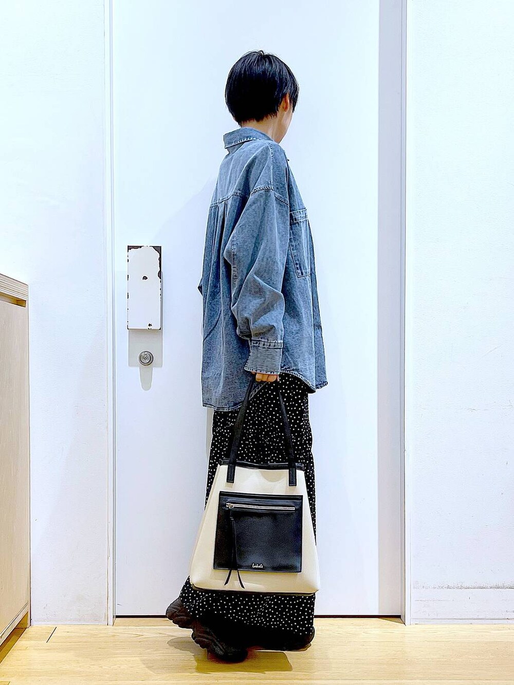 ブラック系のブーツ、ブルー系のシャツ/ブラウス、ホワイト系のトートバッグを着用したレディースの春コーディネートの4枚目の写真