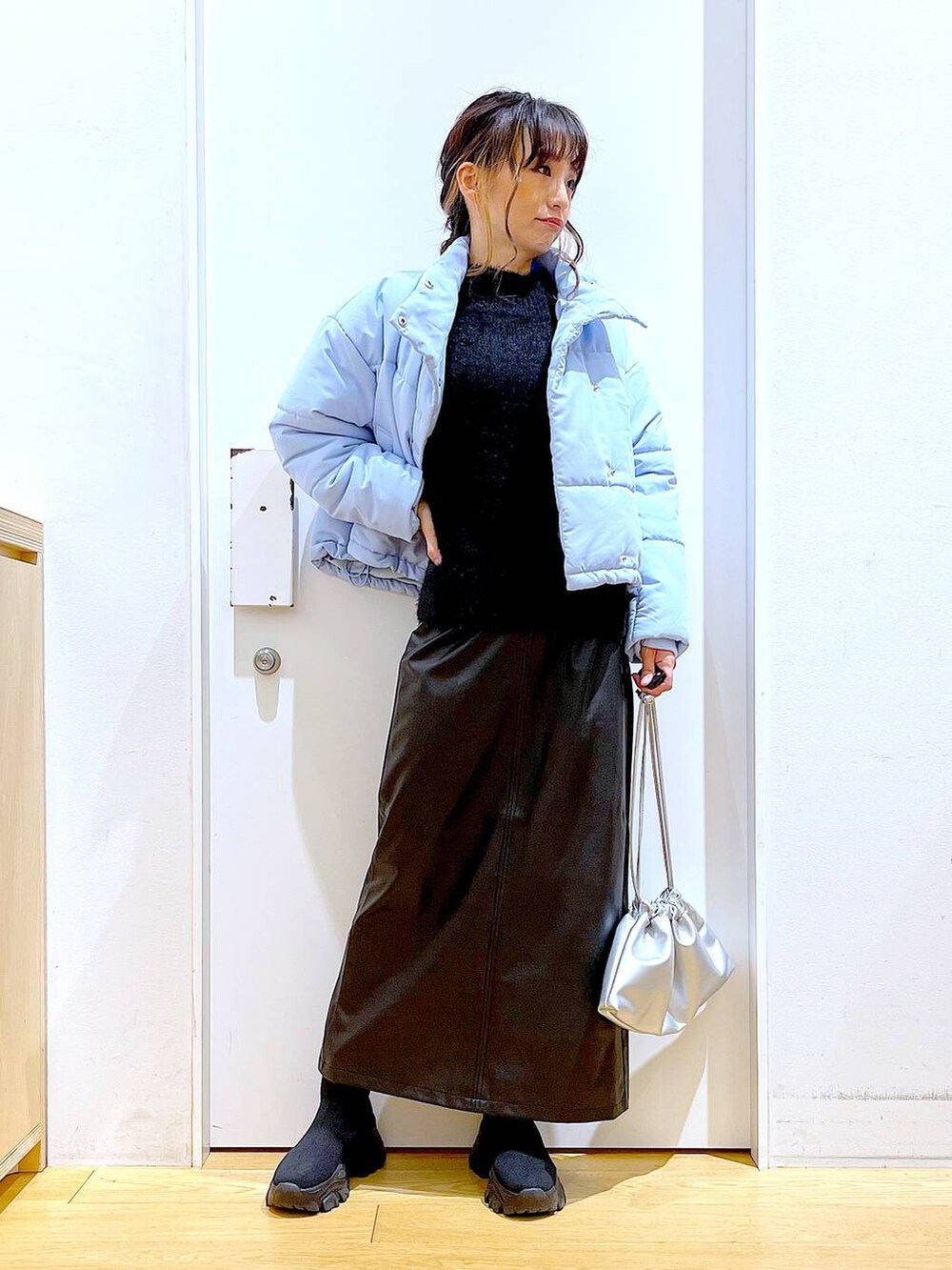 ブラック系のブーツ、シルバー系のショルダーバッグ、ブルー系のナイロンジャケットを着用したレディースの冬コーディネートの2枚目の写真
