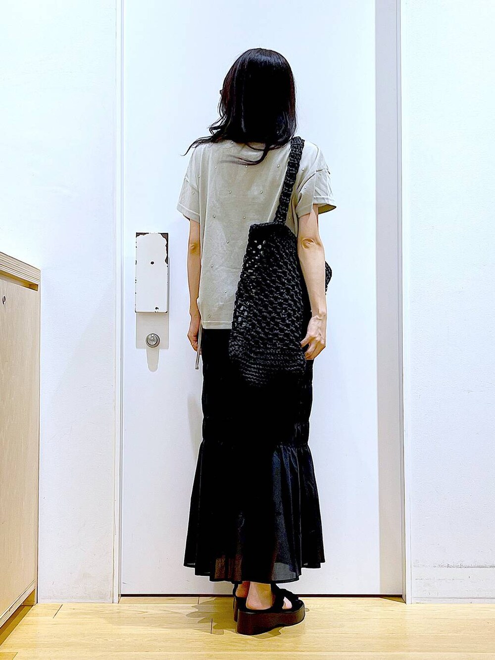 ブラック系のサンダル、ブラック系のスカート、ブラック系のトートバッグを着用したレディースの夏コーディネートの5枚目の写真