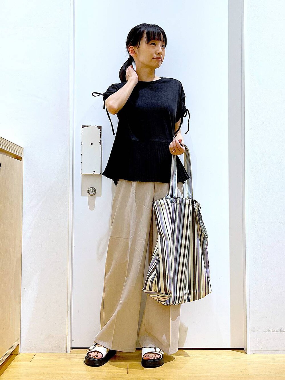 ホワイト系のサンダル、グリーン系のトートバッグ、ベージュ系のスラックスを着用したレディースの秋コーディネートの2枚目の写真