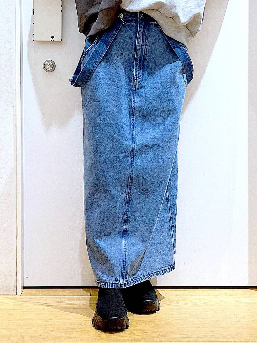 ブラック系のショルダーバッグ、ブラック系のブーツ、ブルー系のジャンパースカートを着用したレディースの春コーディネートの8枚目の写真