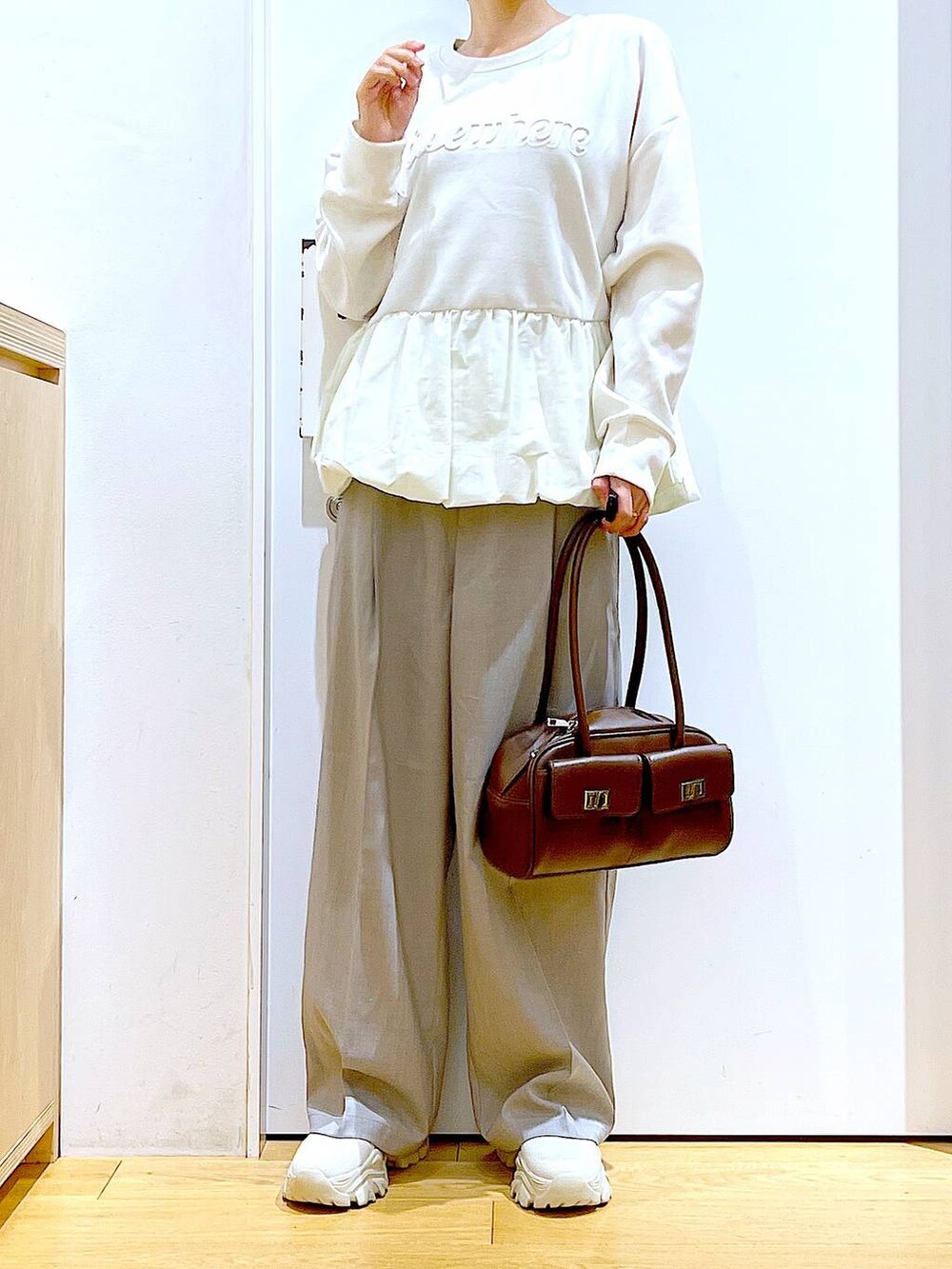 ブラウン系のハンドバッグ、ベージュ系のブーツ、ベージュ系のスウェットを着用したレディースの冬コーディネートの6枚目の写真