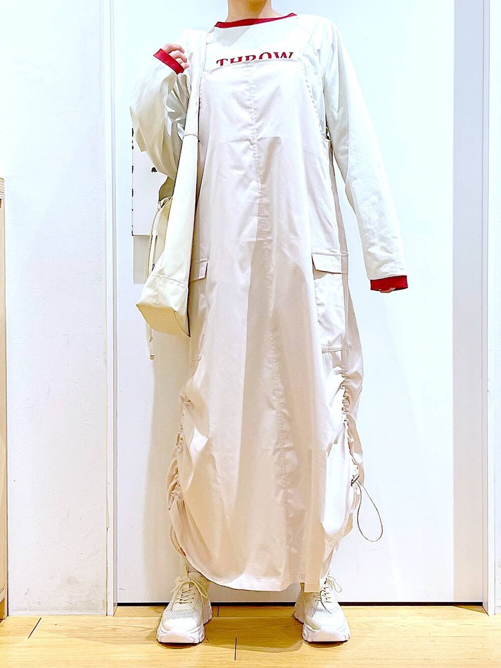 ホワイト系のスニーカー、ベージュ系のジャンパースカート、ベージュ系のTシャツ/カットソーを着用したレディースの春コーディネートの6枚目の写真