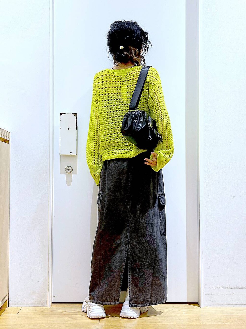 グレー系のデニムスカート、ベージュ系のスニーカー、ブラック系のショルダーバッグを着用したレディースの春コーディネートの5枚目の写真