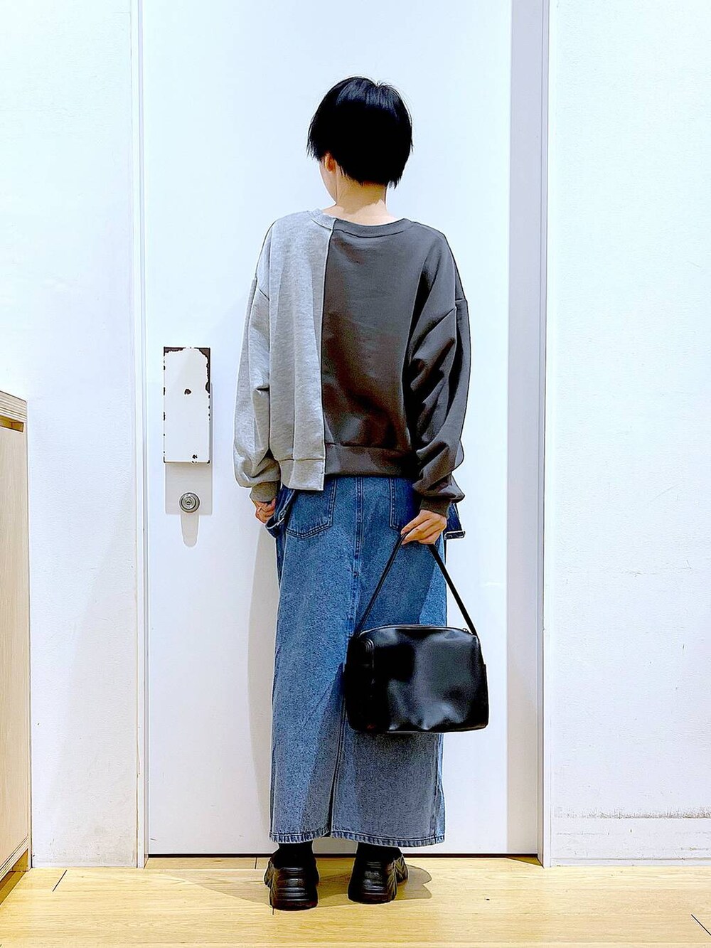 ブラック系のショルダーバッグ、ブラック系のブーツ、ブルー系のジャンパースカートを着用したレディースの春コーディネートの5枚目の写真