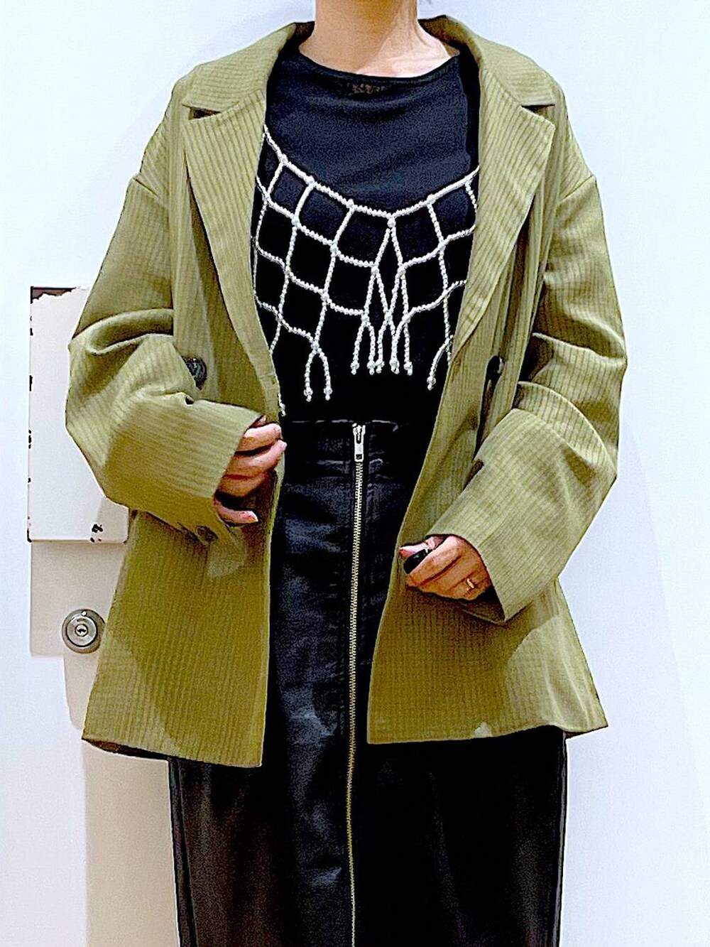 ホワイト系のベスト、ブラック系のスカート、ブラック系のショルダーバッグを着用したレディースの秋コーディネートの7枚目の写真