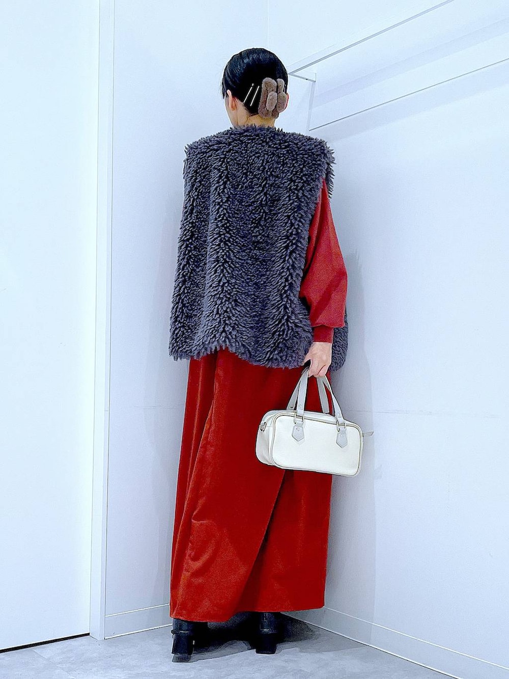 グレー系のベスト、ブラック系のブーツ、ホワイト系のショルダーバッグを着用したレディースの秋コーディネートの5枚目の写真