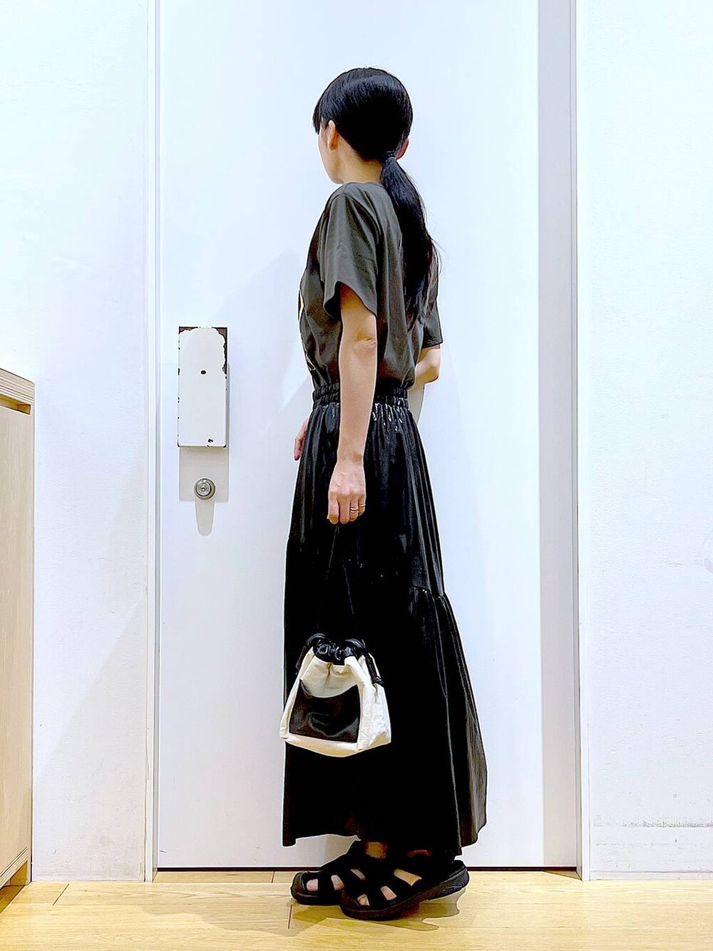 ホワイト系のショルダーバッグ、ブラック系のスリッポン、グレー系のTシャツ/カットソーを着用したレディースの夏コーディネートの3枚目の写真