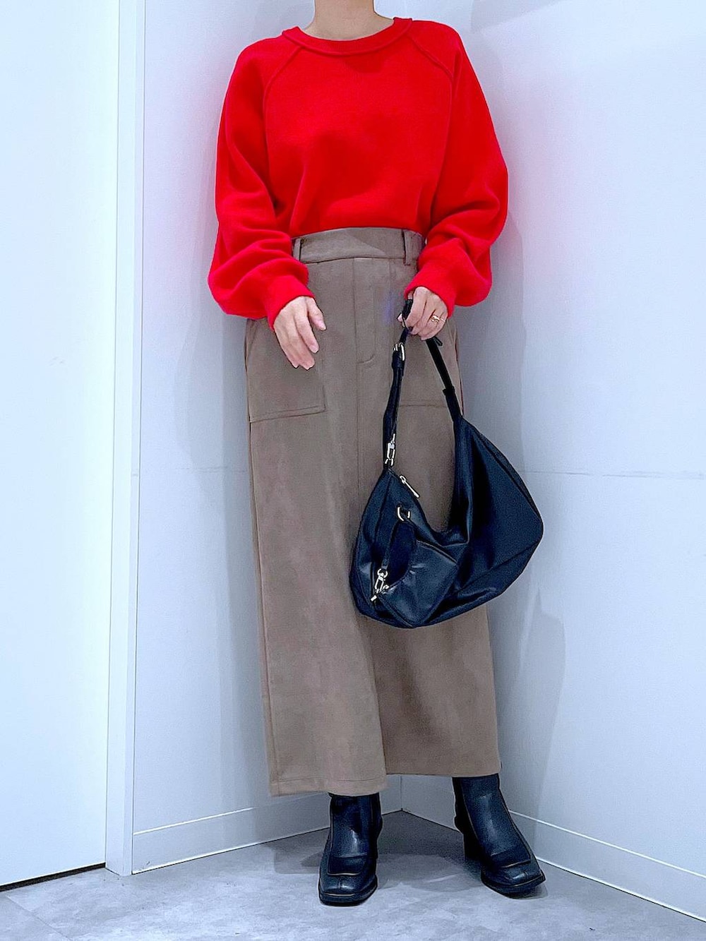 レッド系のニット/セーター、ブラック系のブーツ、ブラック系のショルダーバッグを着用したレディースの冬コーディネートの6枚目の写真