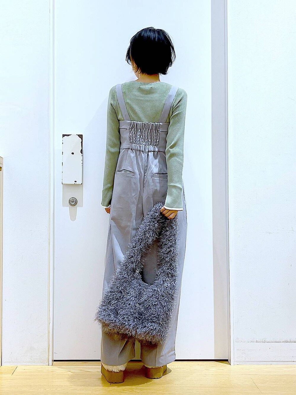 グリーン系のニット/セーター、グレー系のサロペット/オーバーオール、グレー系のショルダーバッグを着用したレディースの秋コーディネートの5枚目の写真