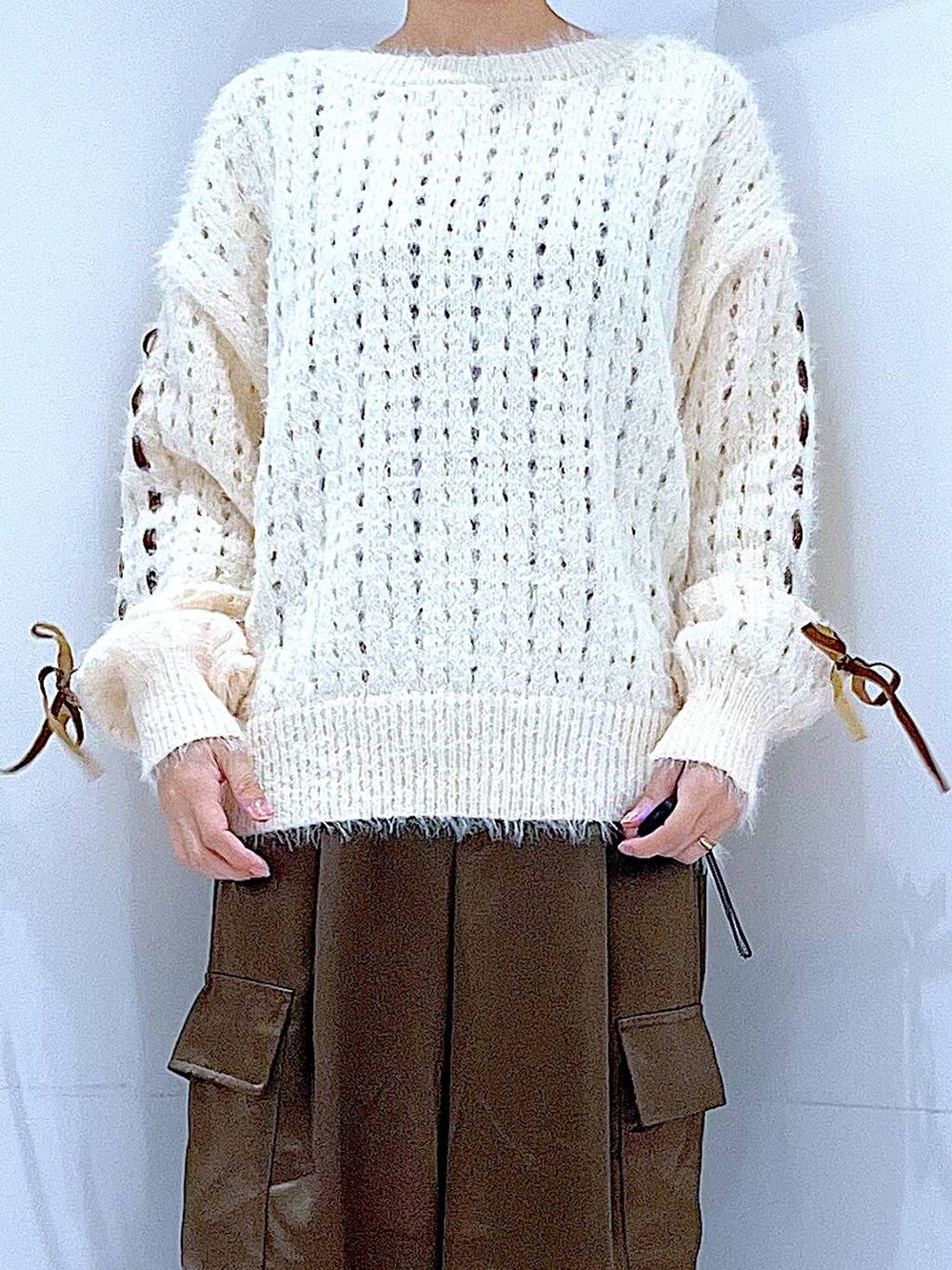 ブラック系のブーツ、ホワイト系のニット/セーター、グリーン系のカーゴパンツを着用したレディースの冬コーディネートの7枚目の写真