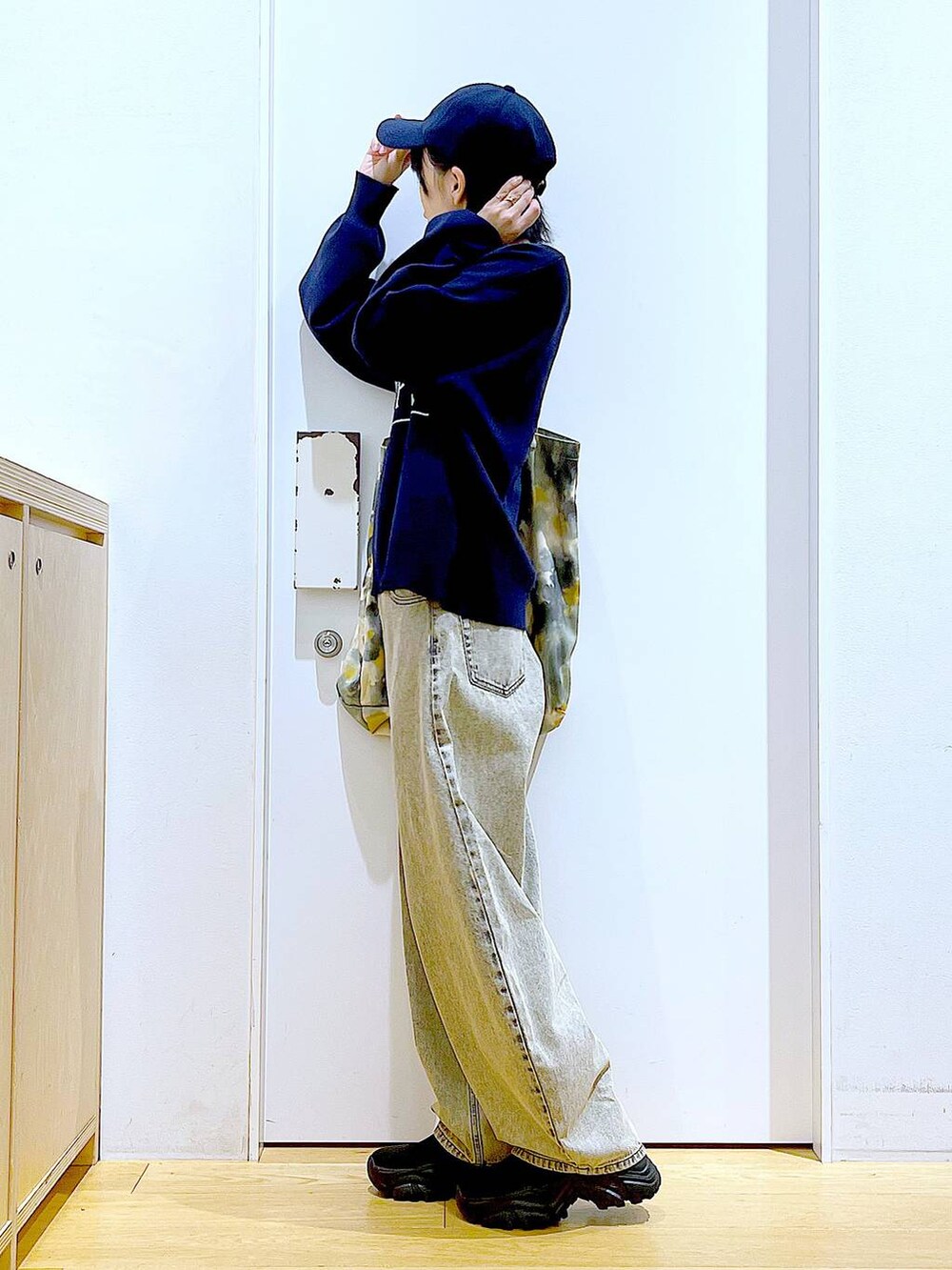 ブラック系のブーツ、ベージュ系のデニムパンツ、イエロー系のトートバッグを着用したレディースの冬コーディネートの3枚目の写真