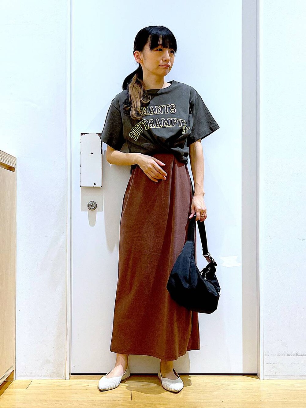 レッド系のワンピース、ブラック系のショルダーバッグ、ホワイト系のパンプスを着用したレディースの春コーディネートの2枚目の写真