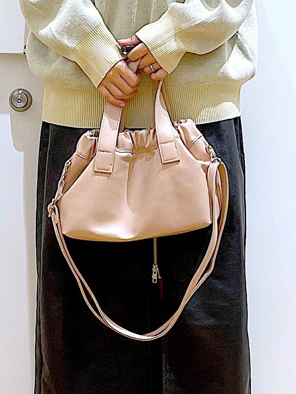 ブラック系のスカート、ブラック系のブーツ、ピンク系のショルダーバッグを着用したレディースの冬コーディネートの9枚目の写真