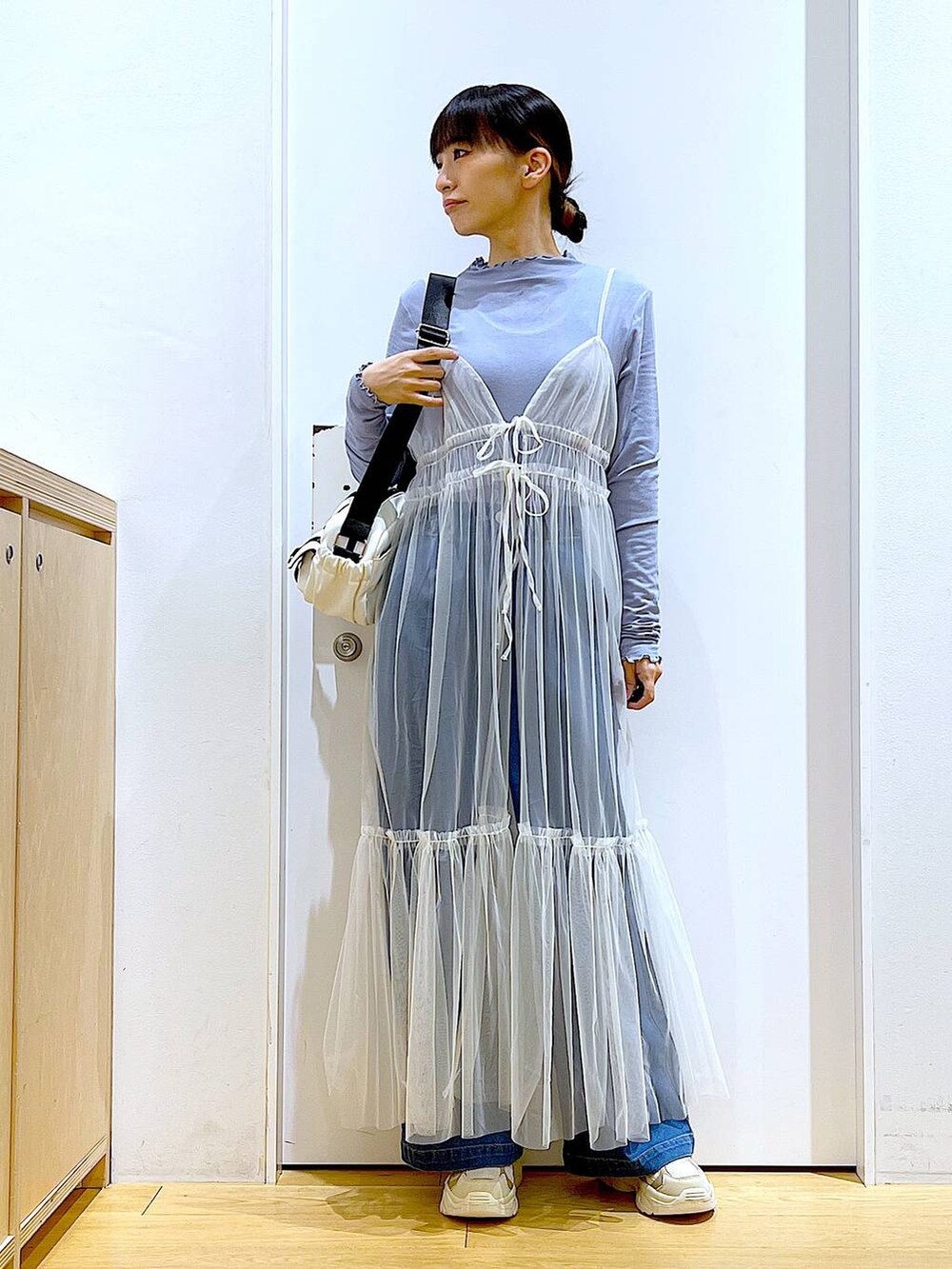 ブルー系のデニムパンツ、ホワイト系のワンピース、ベージュ系のスニーカーを着用したレディースの冬コーディネートの2枚目の写真