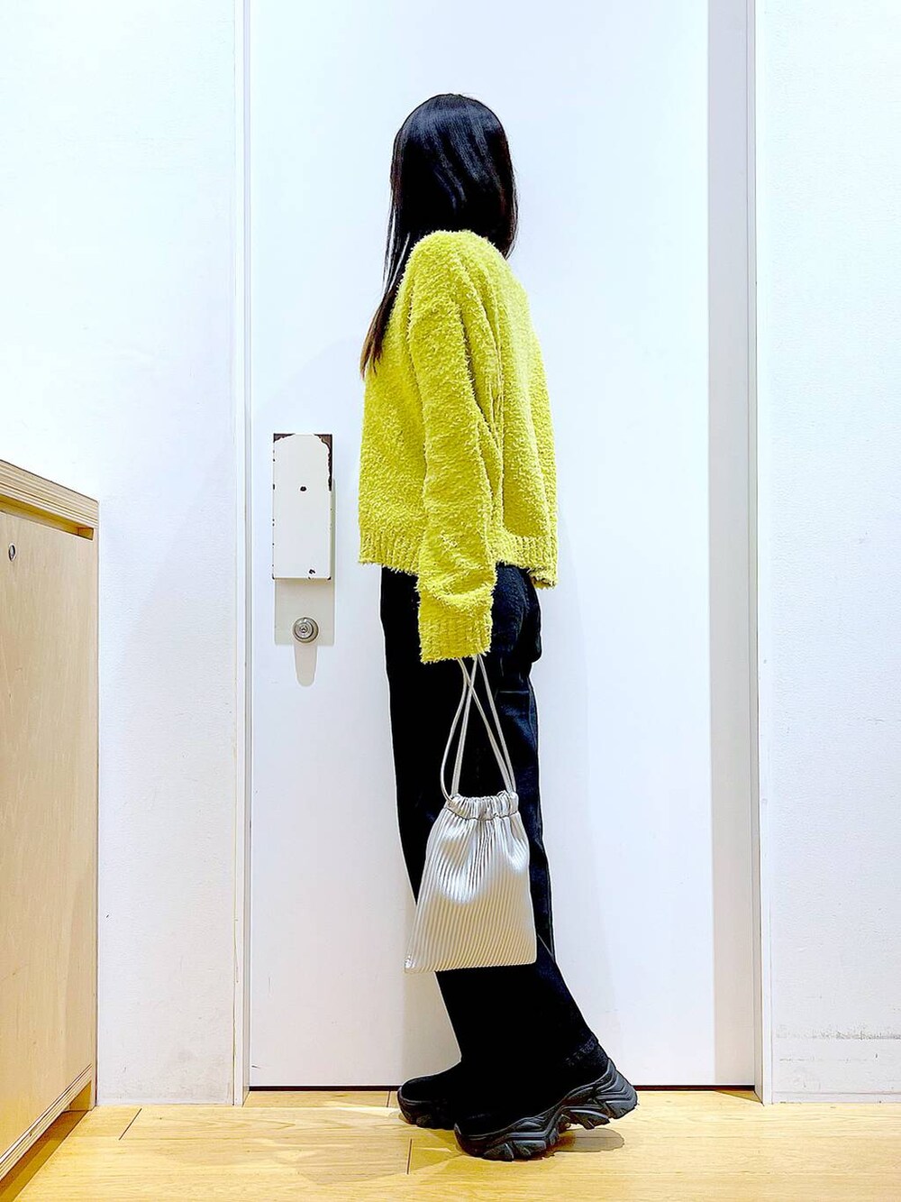 グリーン系のニット/セーター、グレー系のデニムパンツ、シルバー系のショルダーバッグを着用したレディースの冬コーディネートの3枚目の写真