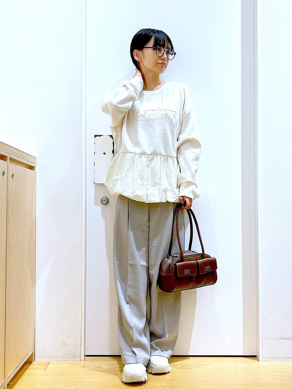 ブラウン系のハンドバッグ、ベージュ系のブーツ、ベージュ系のスウェットを着用したレディースの冬コーディネートの2枚目の写真