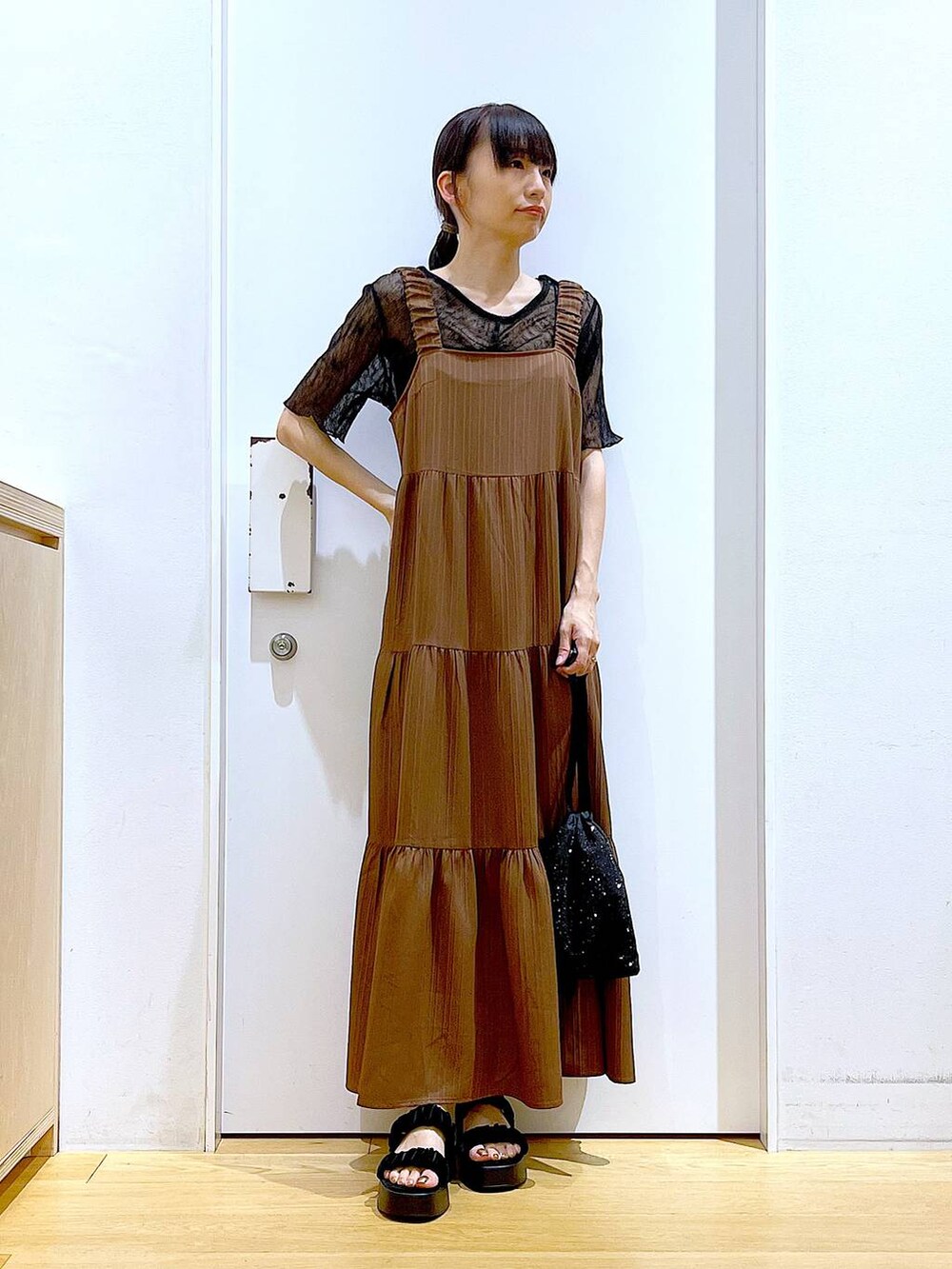 ブラック系のサンダル、ブラック系のショルダーバッグ、ベージュ系のワンピースを着用したレディースの夏コーディネートの2枚目の写真