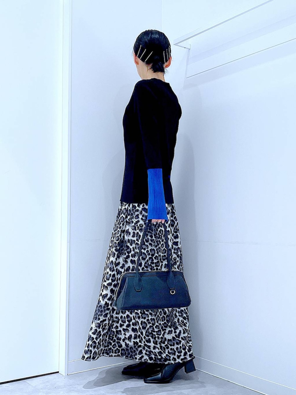 ブラック系のニット/セーター、ブラック系のブーツ、グレー系のスカートを着用したレディースの秋コーディネートの3枚目の写真