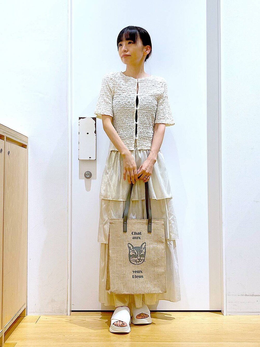 ホワイト系のサンダル、グレー系のトートバッグ、ゴールド系のスカートを着用したレディースの夏コーディネートの2枚目の写真