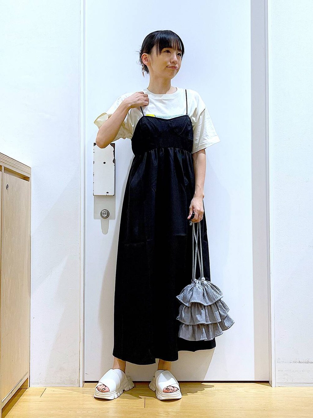 ホワイト系のサンダル、ベージュ系のTシャツ/カットソー、ブラック系のワンピースを着用したレディースの夏コーディネートの2枚目の写真