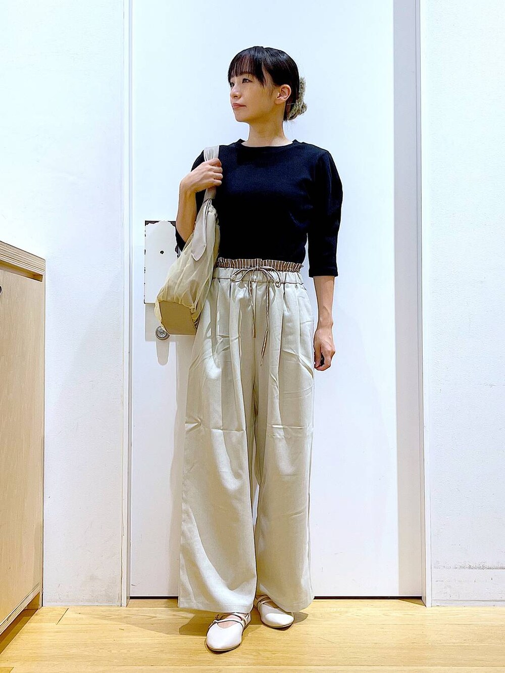 ベージュ系のトートバッグ、ホワイト系のパンプス、ブラック系のTシャツ/カットソーを着用したレディースの秋コーディネートの2枚目の写真