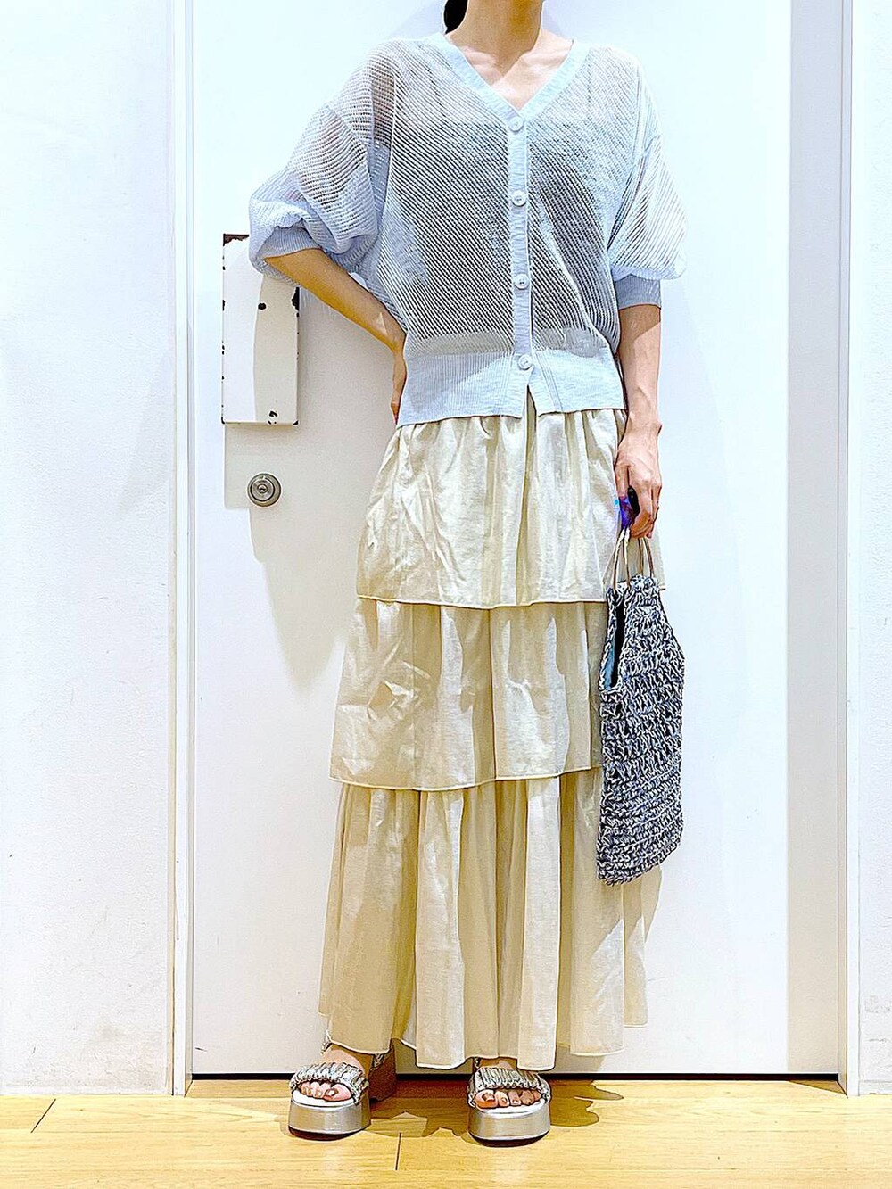 シルバー系のサンダル、ブルー系のハンドバッグ、ゴールド系のスカートを着用したレディースの夏コーディネートの6枚目の写真
