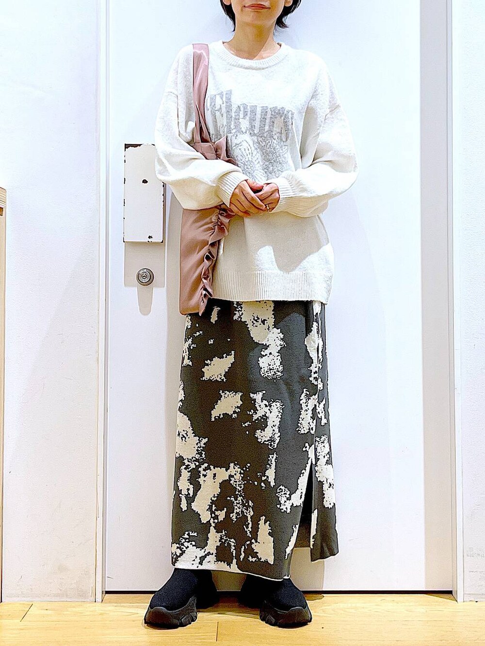 グレー系のスカート、ブラック系のブーツ、ベージュ系のニット/セーターを着用したレディースの秋コーディネートの6枚目の写真