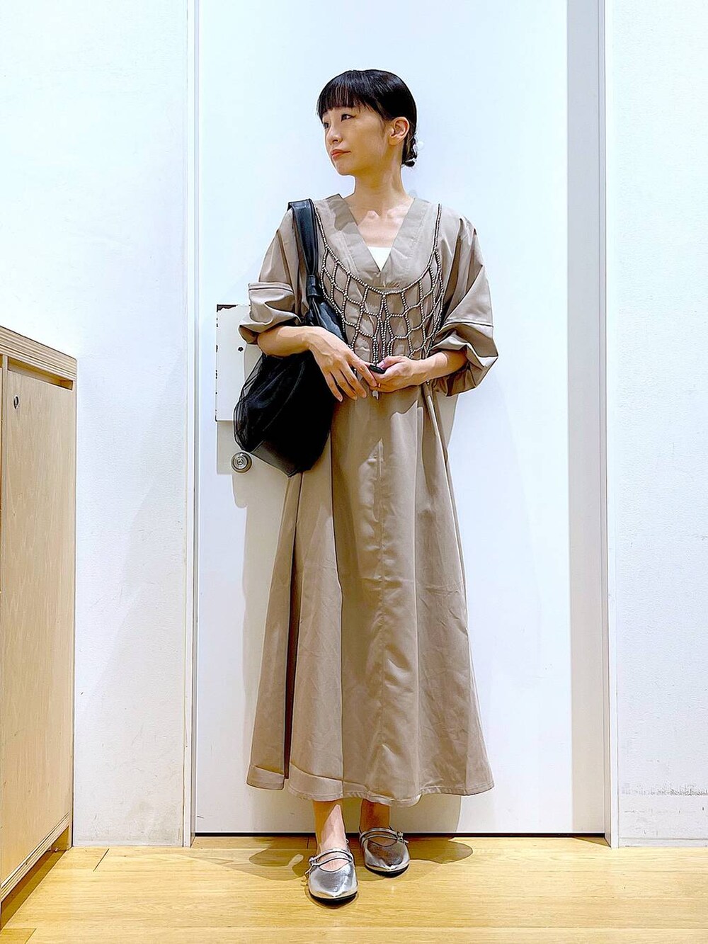 ブラック系のトートバッグ、ベージュ系のワンピース、シルバー系のパンプスを着用したレディースの夏コーディネートの2枚目の写真