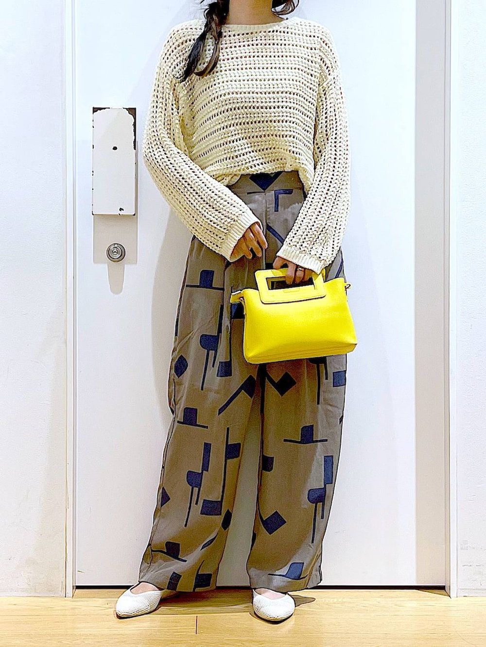 ホワイト系のニット/セーター、イエロー系のショルダーバッグ、ホワイト系のパンプスを着用したレディースの春コーディネートの6枚目の写真