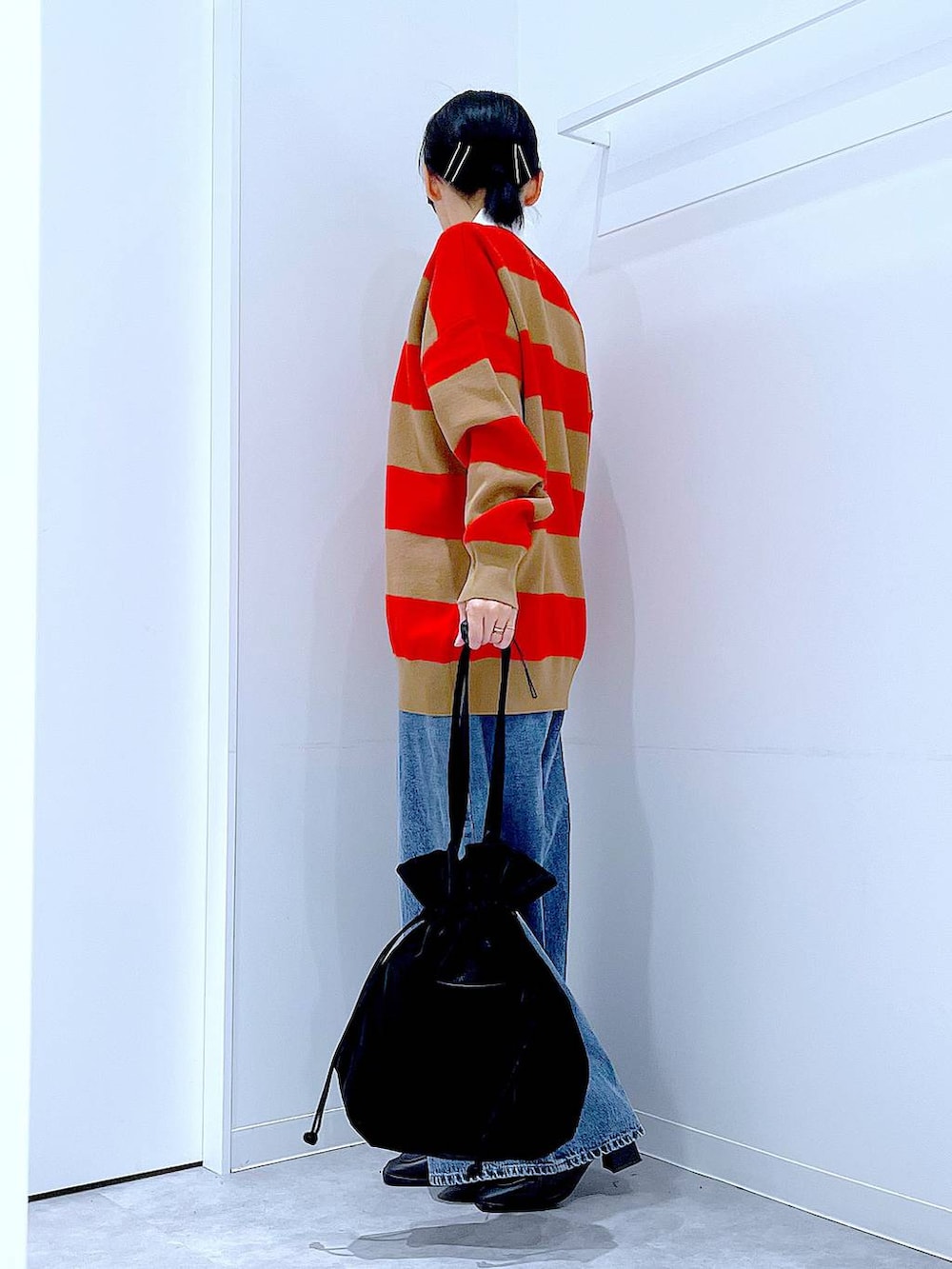 ブラック系のトートバッグ、レッド系のニット/セーター、ブルー系のデニムパンツを着用したレディースの冬コーディネートの3枚目の写真