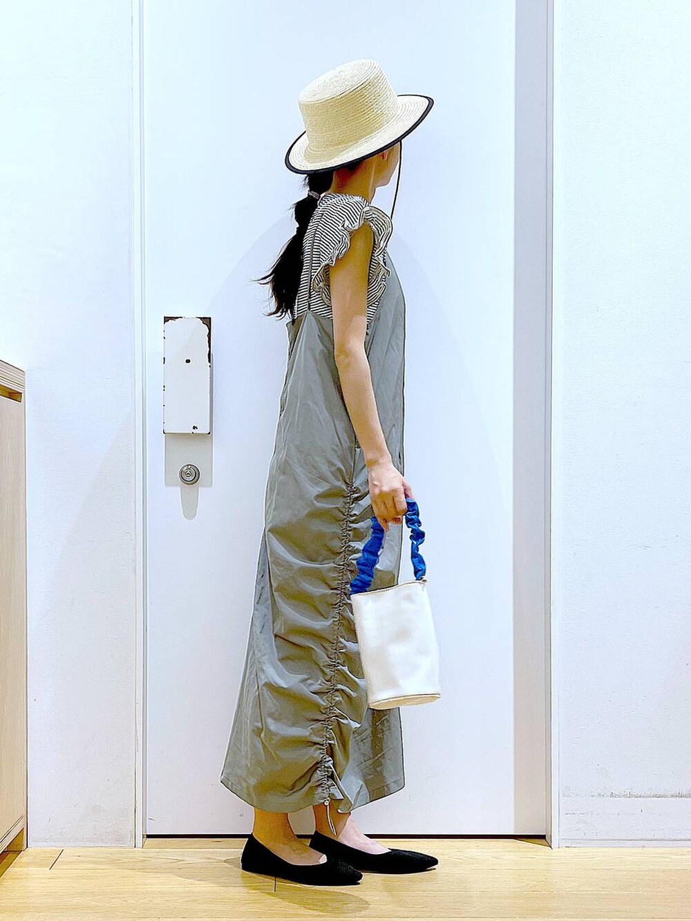 ブルー系のショルダーバッグ、ブラック系のパンプス、グリーン系のワンピースを着用したレディースの春コーディネートの4枚目の写真