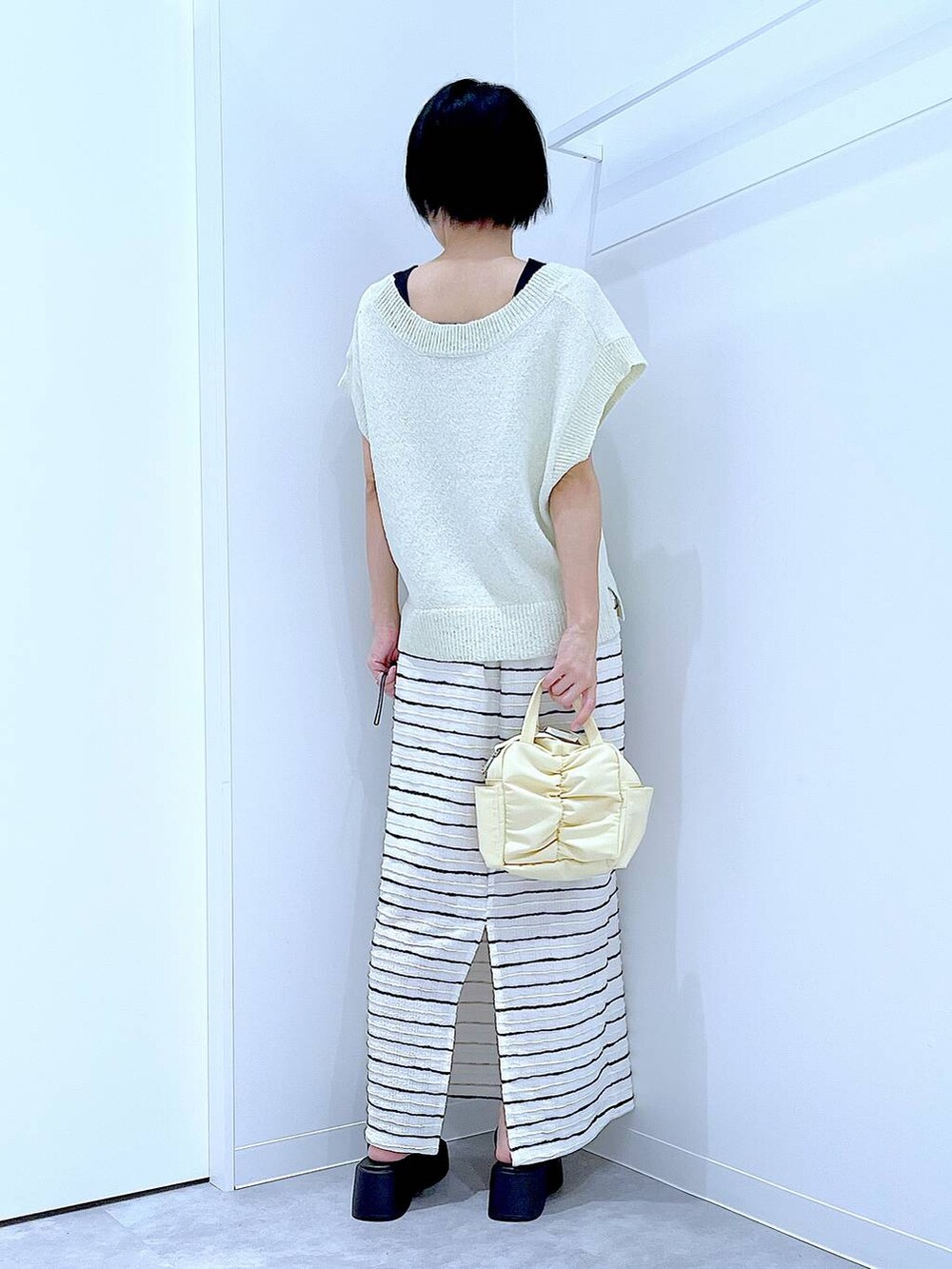 ブラック系のサンダル、イエロー系のショルダーバッグ、ホワイト系のスカートを着用したレディースの夏コーディネートの5枚目の写真