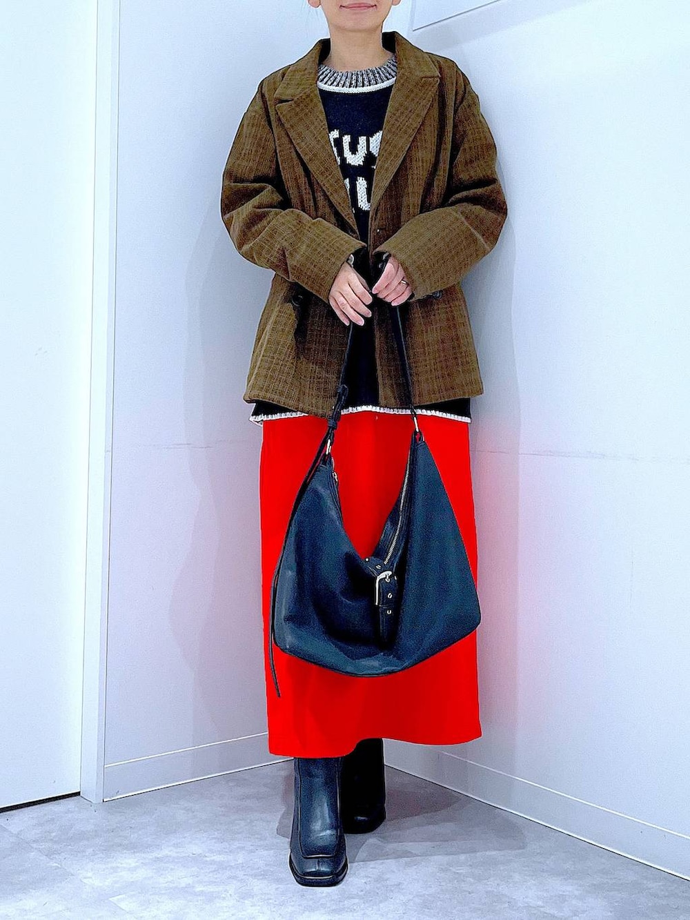 レッド系のスカート、ブラック系のブーツ、ブラック系のショルダーバッグを着用したレディースの冬コーディネートの6枚目の写真