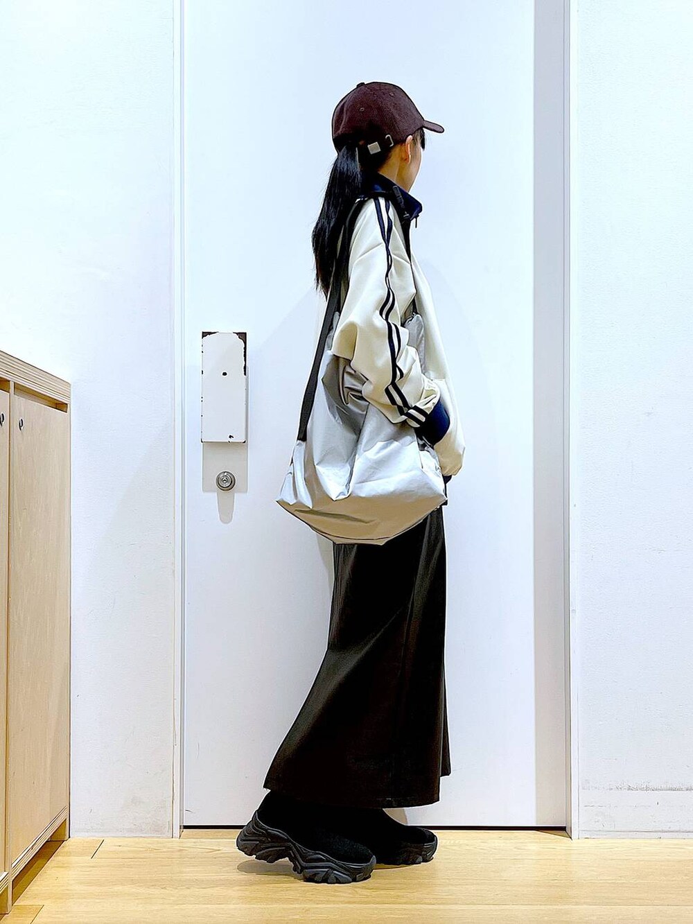 ブラック系のブーツ、ブラック系のスカート、シルバー系のショルダーバッグを着用したレディースの冬コーディネートの4枚目の写真