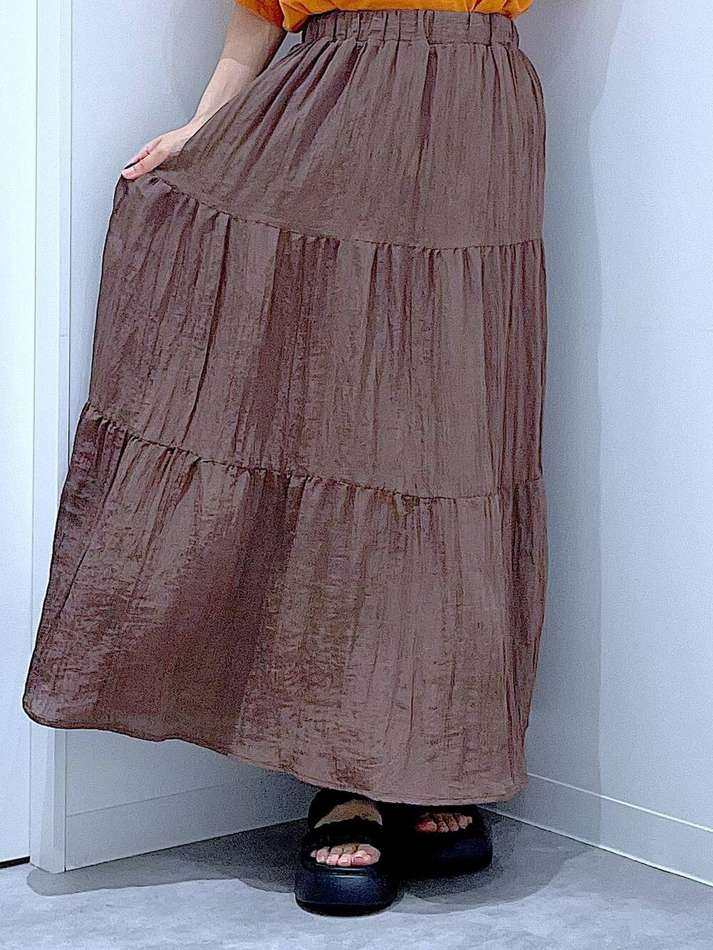 ベージュ系のショルダーバッグ、ブラック系のサンダル、オレンジ系のTシャツ/カットソーを着用したレディースの夏コーディネートの8枚目の写真