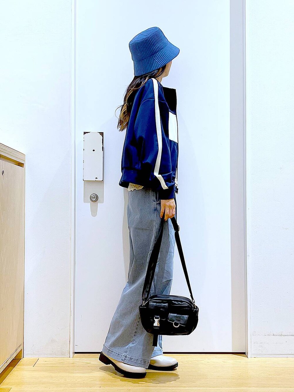 ブルー系のデニムパンツ、ベージュ系のブーツ、ブラック系のショルダーバッグを着用したレディースの冬コーディネートの4枚目の写真