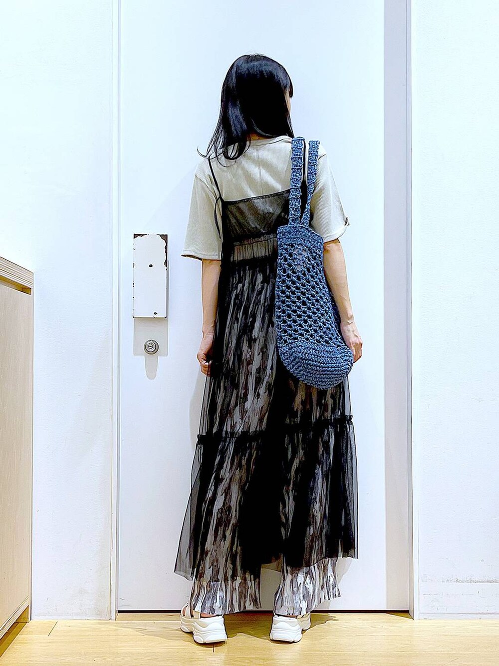 ブラック系のワンピース、ホワイト系のサンダル、ブルー系のトートバッグを着用したレディースの夏コーディネートの5枚目の写真