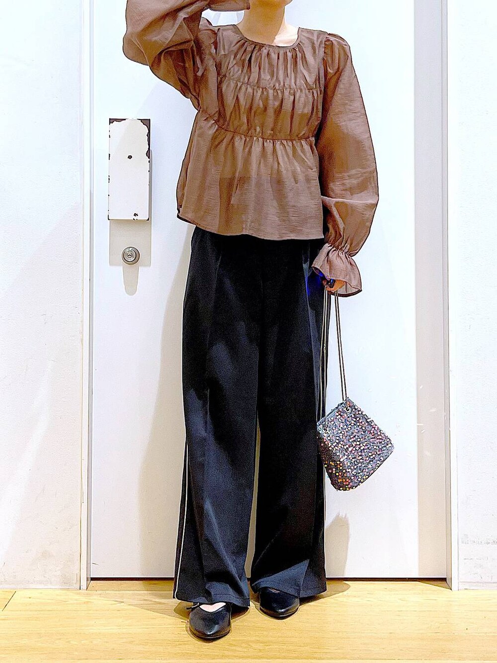 グレー系のショルダーバッグ、ブラック系のスラックス、ブラック系のパンプスを着用したレディースの秋コーディネートの6枚目の写真