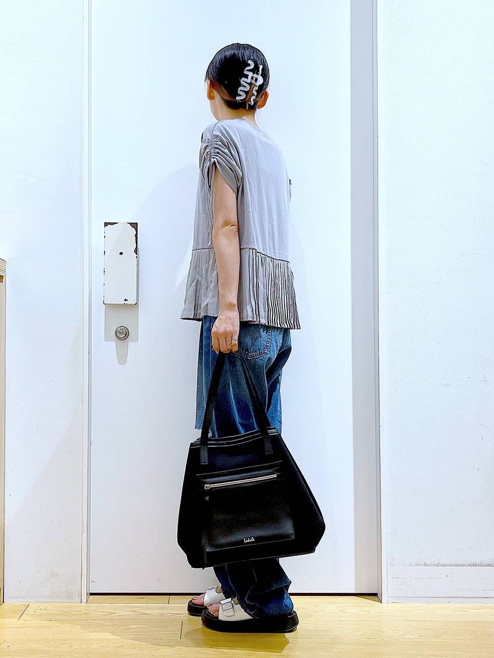 ホワイト系のサンダル、ブラック系のトートバッグ、ブルー系のデニムパンツを着用したレディースの夏コーディネートの3枚目の写真