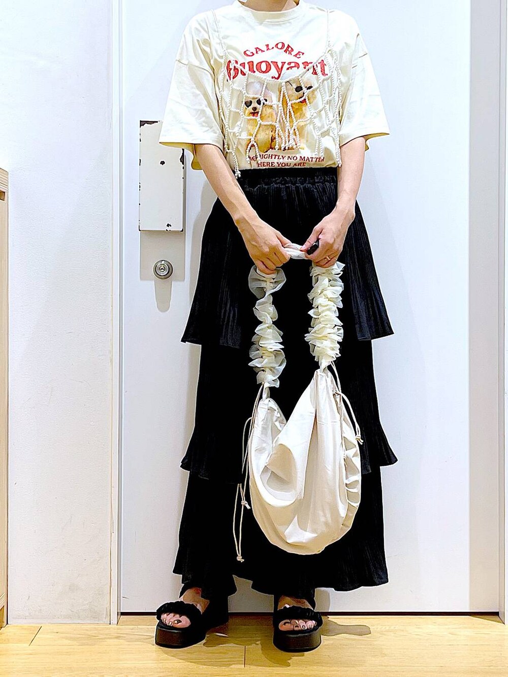 ブラック系のスカート、ブラック系のサンダル、ホワイト系のベストを着用したレディースの秋コーディネートの6枚目の写真