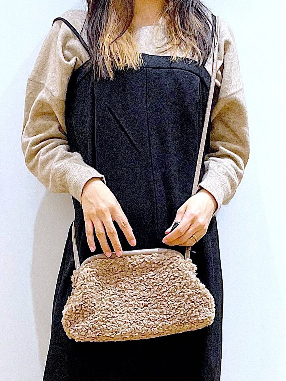 ベージュ系のニット/セーター、ブラック系のブーツ、ブラウン系のクラッチバッグを着用したレディースの冬コーディネートの9枚目の写真