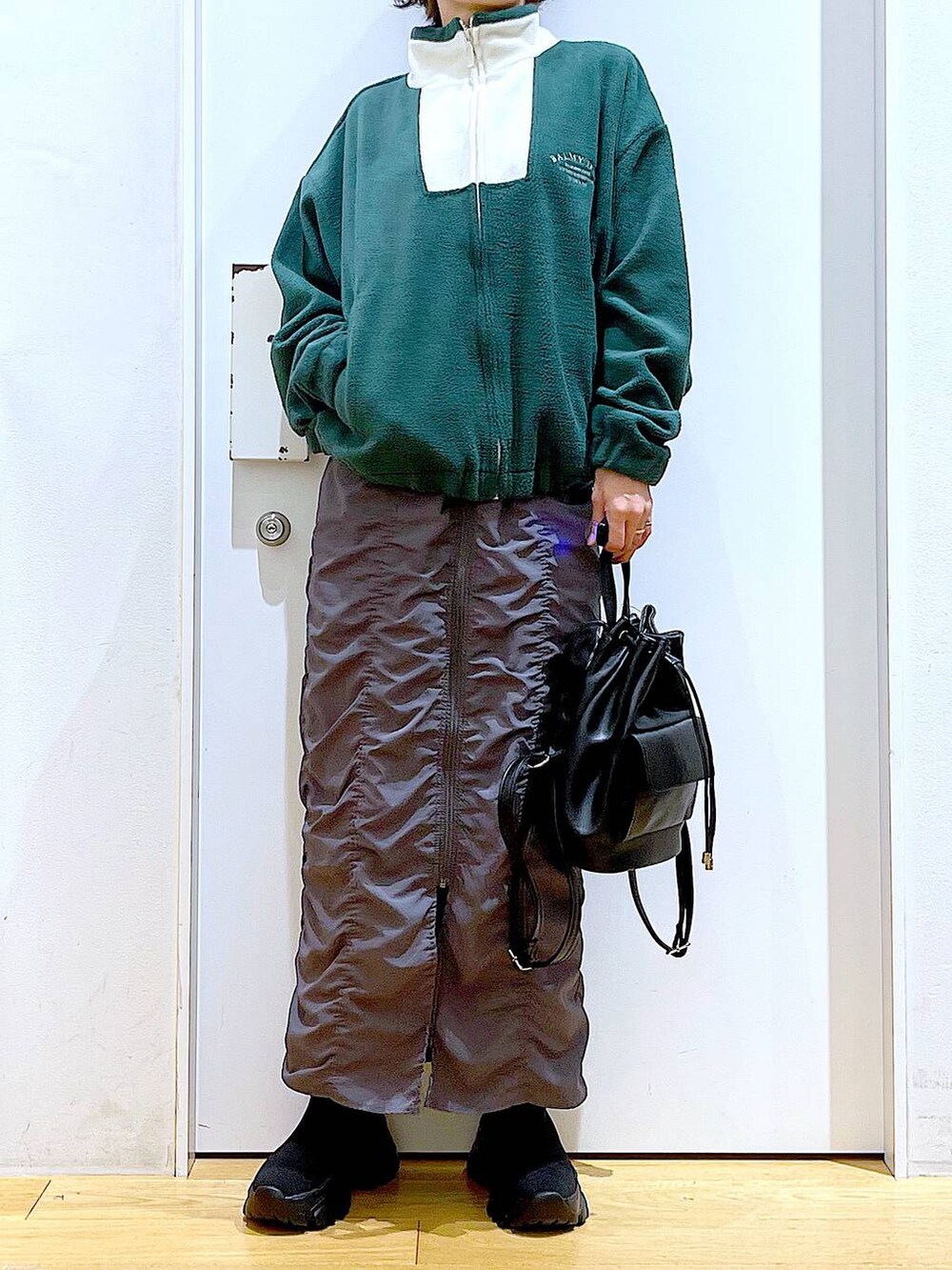 ブラック系のバックパック/リュック、グレー系のスカート、ブラック系のブーツを着用したレディースの冬コーディネートの6枚目の写真