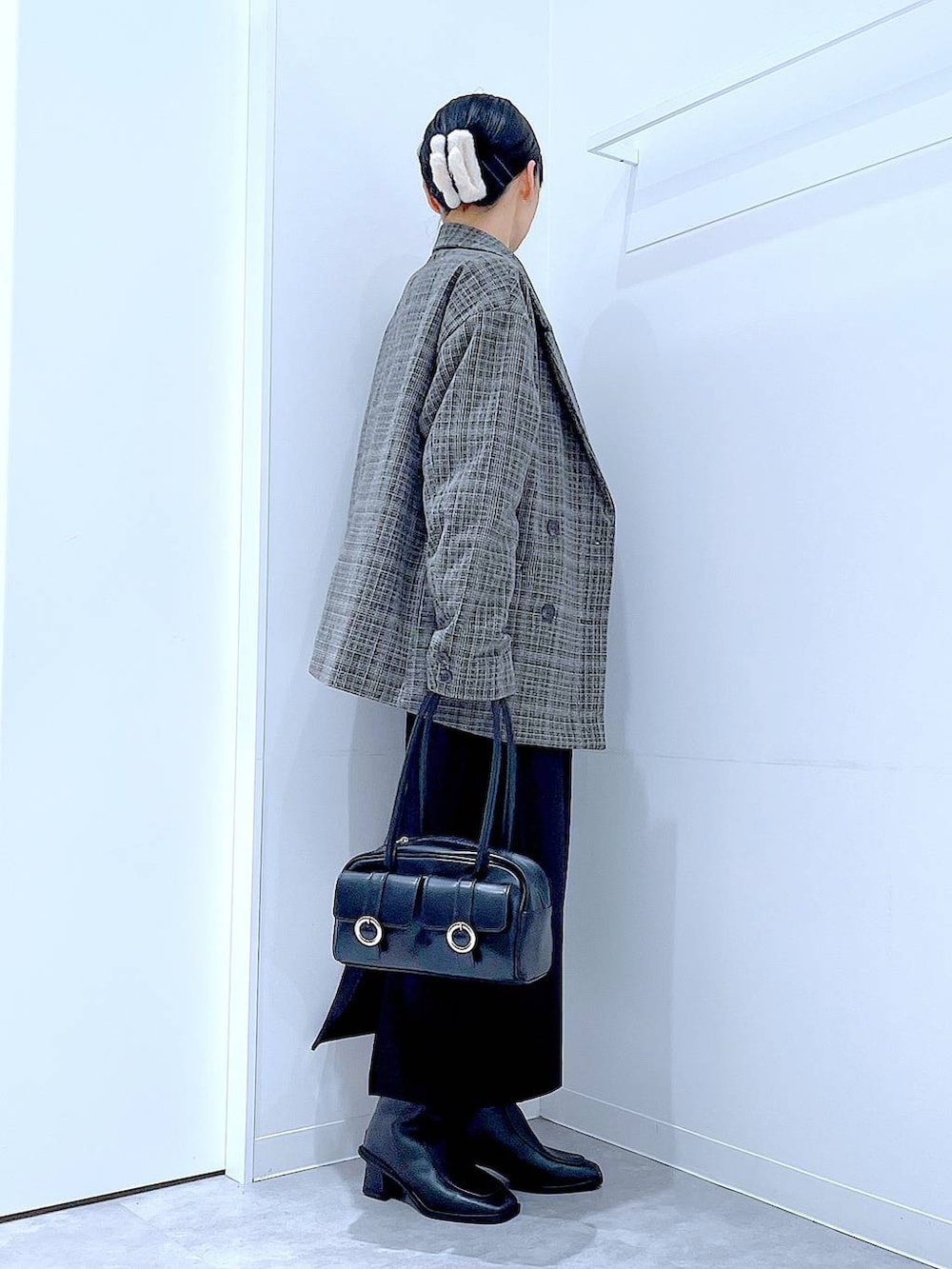 ブラック系のショルダーバッグ、ブラック系のスカート、ブラック系のブーツを着用したレディースの冬コーディネートの4枚目の写真