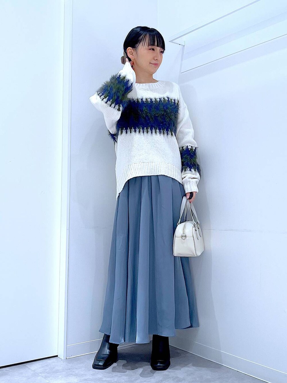 ブラック系のブーツ、ホワイト系のショルダーバッグ、ホワイト系のニット/セーターを着用したレディースの冬コーディネートの2枚目の写真