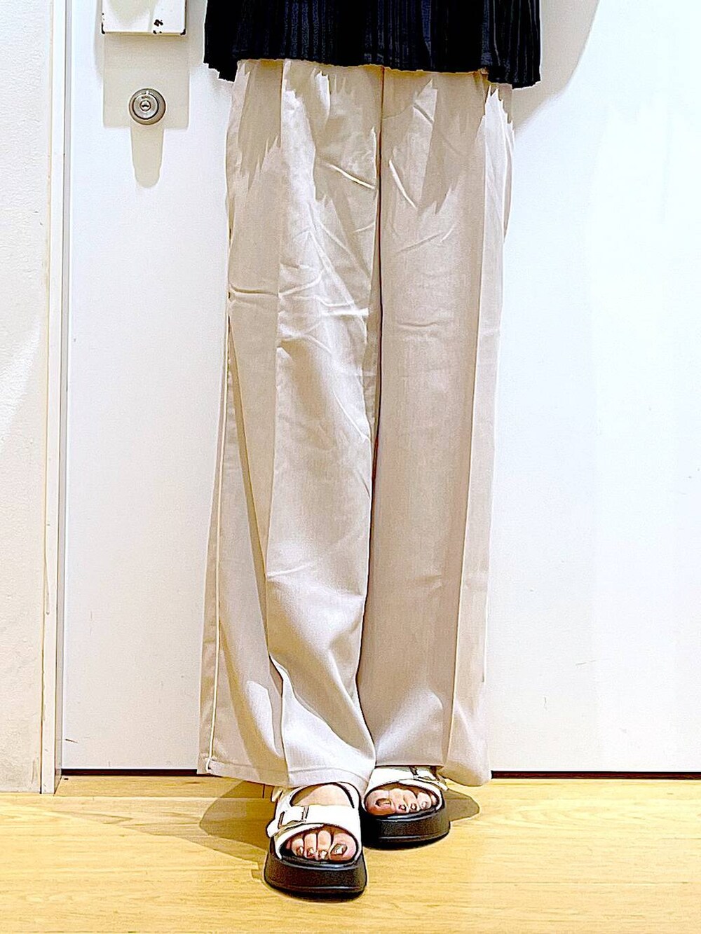 ホワイト系のサンダル、グリーン系のトートバッグ、ベージュ系のスラックスを着用したレディースの秋コーディネートの8枚目の写真