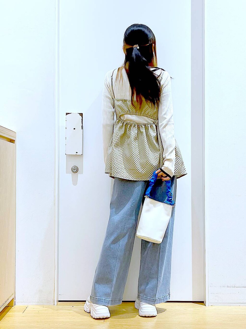 ブルー系のショルダーバッグ、ブルー系のデニムパンツ、ベージュ系のニット/セーターを着用したレディースの春コーディネートの5枚目の写真